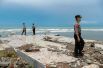 Полицейские разыскивают жертв среди обломков разрушенного прибрежного отеля, пострадавшего от цунами в Пандегланге, Индонезия.