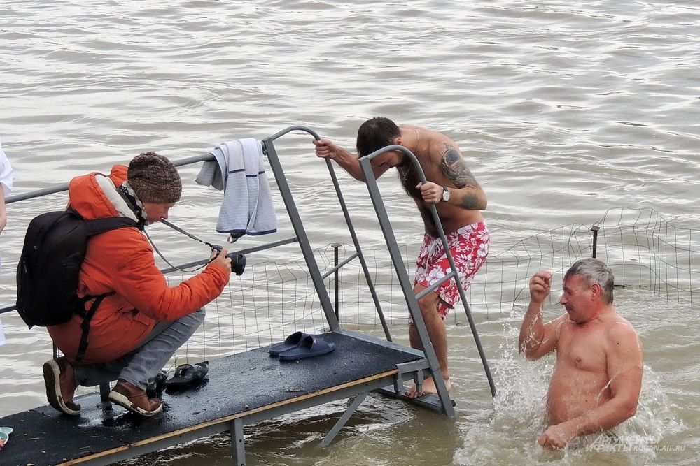 Фотокорреспондент ловит удачный кадр для репортажа о крещении.