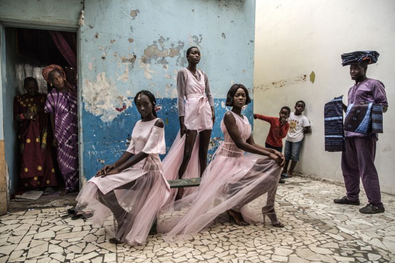 Девушки демонстрируют дизайнерские наряды в окружении любопытных жителей в столице Сенегала Дакар.