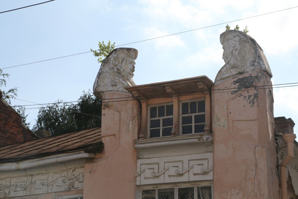 На пилонах здания установлены бюсты-авгуры в виде человеческих голов, склонившихся над шахматной доской.