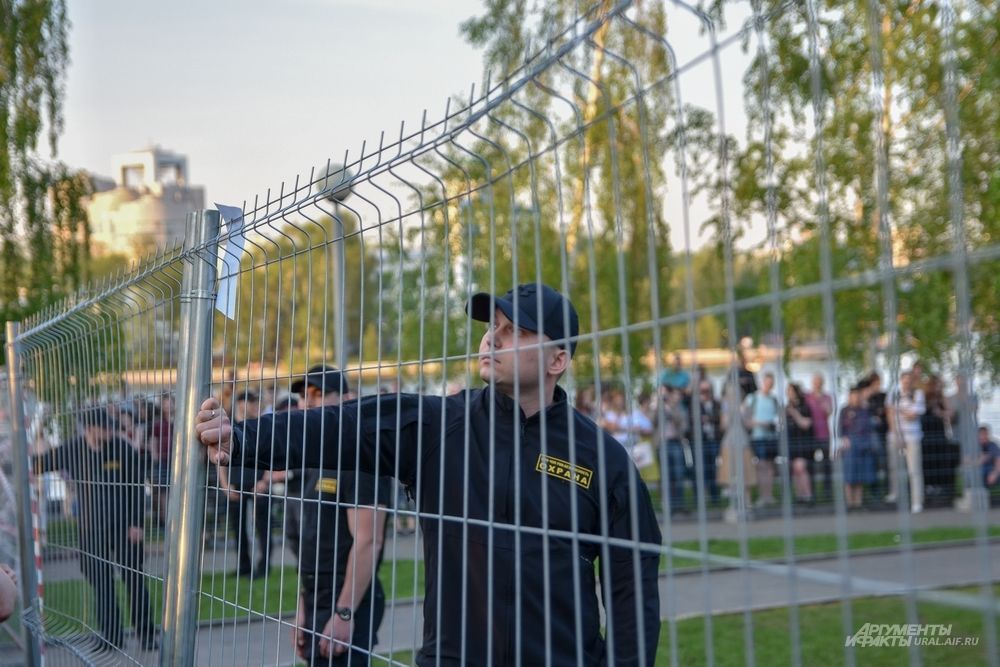 Сотрудник ЧОП читает листовку, повешенную на забор.