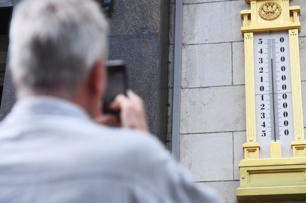 Мужчина фотографирует термометр на здании Государственной Думы.