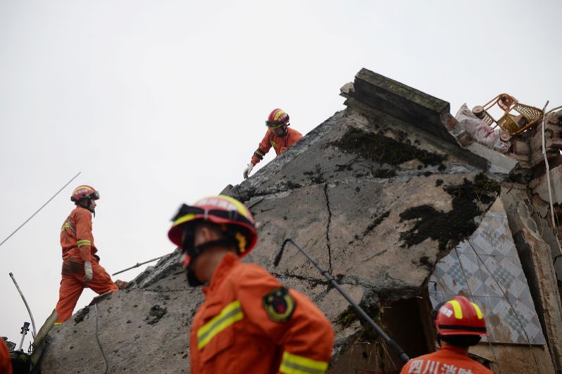 Спасатели на развалинах дома после землетрясения.
