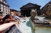 Люди освежаются у фонтана в центре Рима.