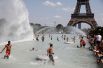 Люди освежаются в фонтанах Трокадеро напротив Эйфелевой башни в Париже.