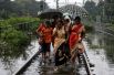 Пассажиры идут по затопленным железнодорожным путям после остановки поезда во время сезона муссонных дождей в Мумбаи, Индия.