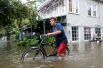 Мужчина с велосипедом на затопленной улице в Мандевилле.