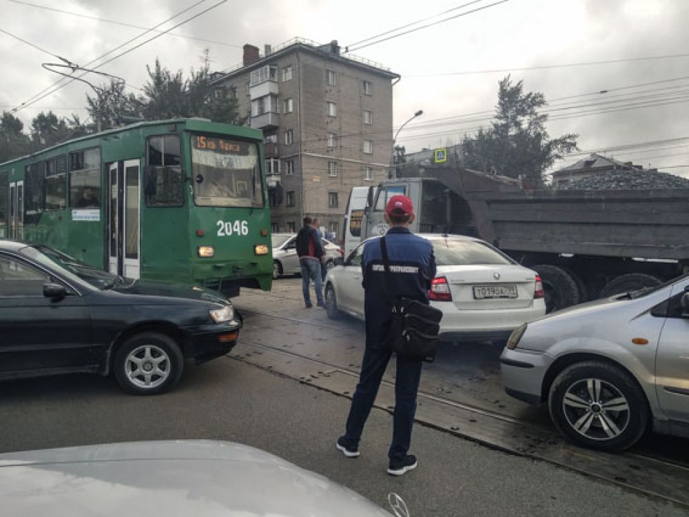 В центре перекрестка стояли трамвай, автомобиль скорой помощи, грузовики и легковушки