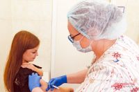 Медсестра Кристина Сергеева делает прививку от кори жительнице Обручевского.