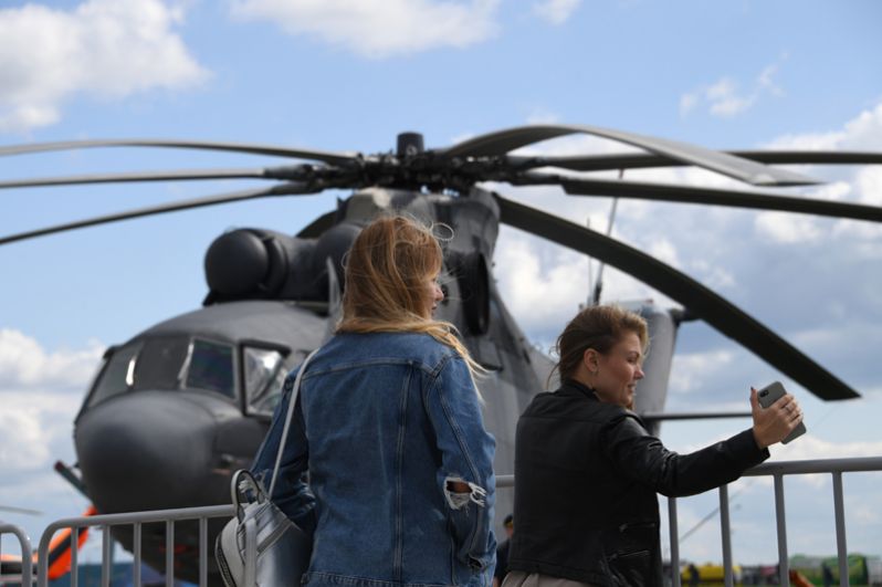 Посетительницы фотографируются на фоне Российского многоцелевого военно-транспортного вертолета Ми-26.