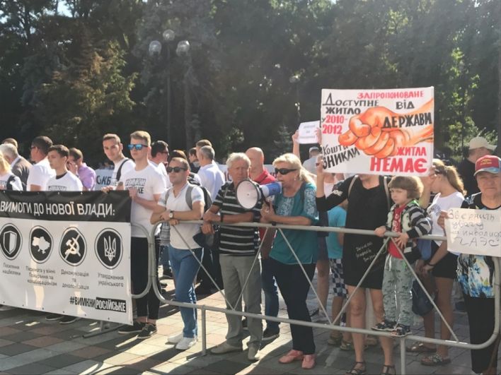 Около 09:00 утра, 29 августа, под зданием парламента, помимо журналистов, собрались митингующие, плакаты которых указывали на ошибки парламента с программой