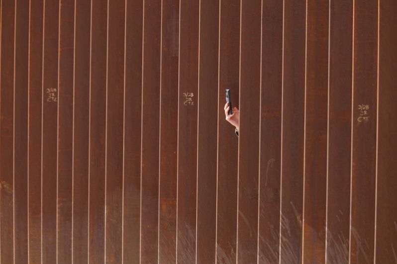 Человек фотографирует Трампа во время его визита к стене на границе США и Мексики.