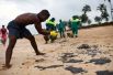 Муниципальные работники убирают нефть на пляже Барра-де-Жакуипе в Камакари.
