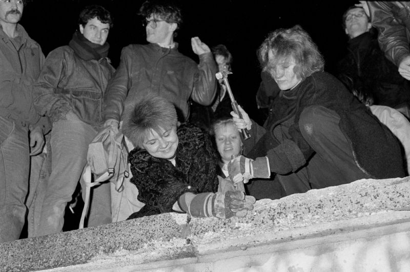 Жители Берлина с молотками и зубилами сидят на Берлинской стены в районе Бранденбургских ворот.
