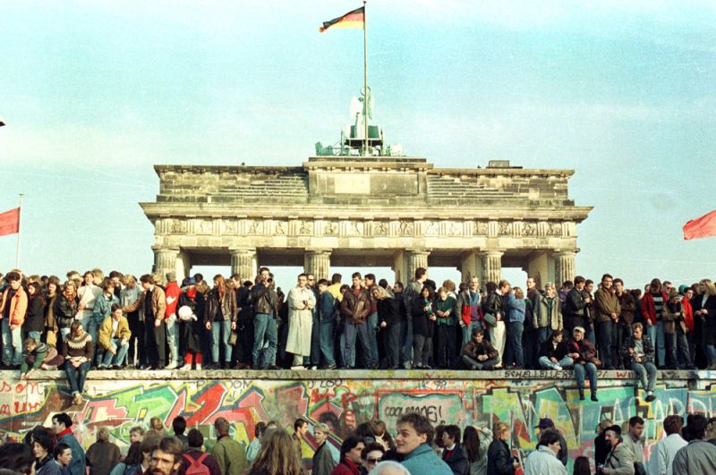 Жители Западного Берлина стоят на Берлинской стене перед Брандебургскими воротами.
