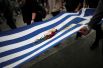 Окровавленный греческий флаг в руках демонстрантов.