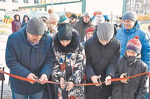 Новосёлы г. Поронайска (Сахалинская обл.) перерезают ленточку у входа в свой новый дом.