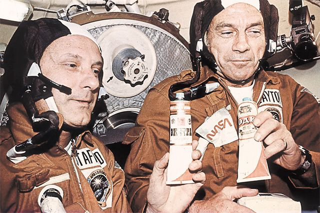 Американские астронавты Том Стаффорд и Дик Слейтон держат тюбики с «русской водкой», которую им дал Алексей Леонов в совместном полёте «Союз» – «Аполлон» в 1975 г.