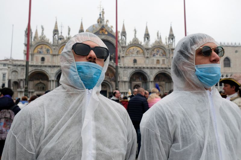 Туристы в масках и защитных костюмах на Венецианском карнавале.