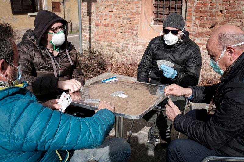 Местные жители в масках играют в карты на улице в Сан-Фьорано.