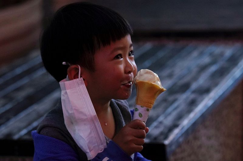 Ребенок ест мороженое возле магазина в первый день его открытия, Сяньнин, провинция Хубэй.