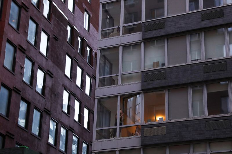 Девушка аплодирует медицинским работникам из окна своей квартиры на Манхэттене.