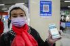Женщина показывает экран своего мобильного телефона с открытой программой для сканирования QR-кода на станции метро в Ухане.