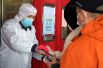 Сотрудник сканирует QR-коды жителей у входа в супермаркет в Чжэнчжоу.