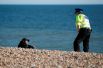 Полицейский убеждает мужчину уйти с пляжа в Брайтоне, Великобритания.