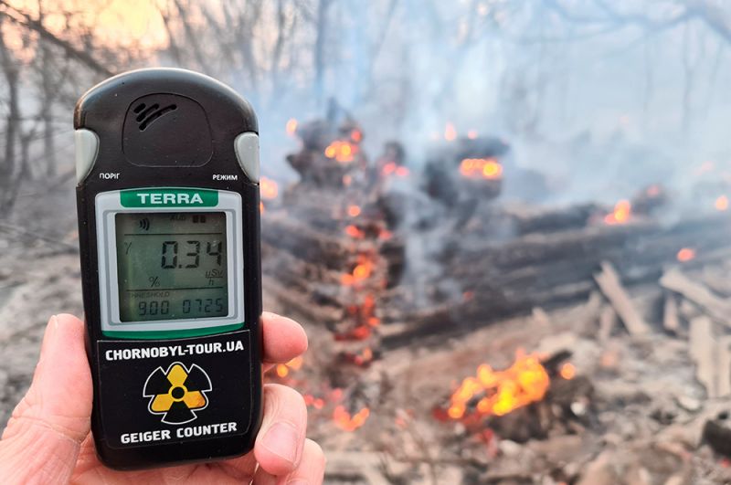 Счетчик Гейгера измеряет уровень радиации на месте пожара неподалеку от села Раговка.