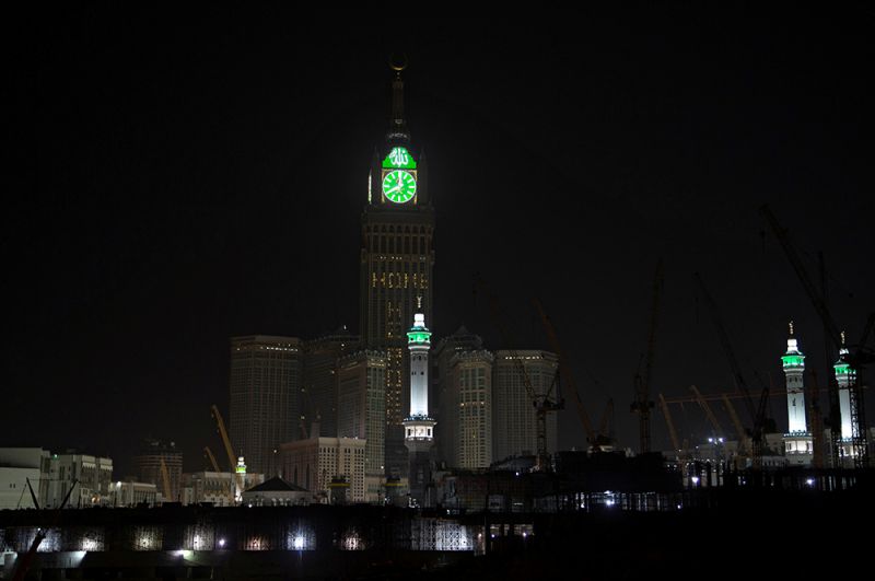Башня с часами Большой мечети в Мекке, Саудовская Аравия, во время комендантского часа. Надпись рядом с часами: «Домашние герои».