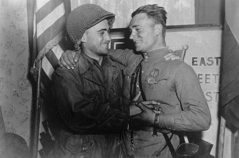 Лейтенант Робертсон и лейтенант Сильвашко на фоне надписи «Восток встречается с Западом», символизирующей историческую встречу союзников на Эльбе.