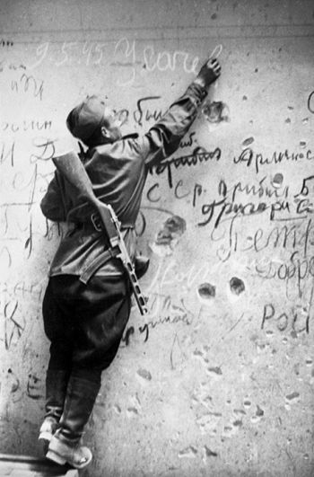 Советский боец Егор Усачев делает памятную надпись на стене Рейхстага.Руины