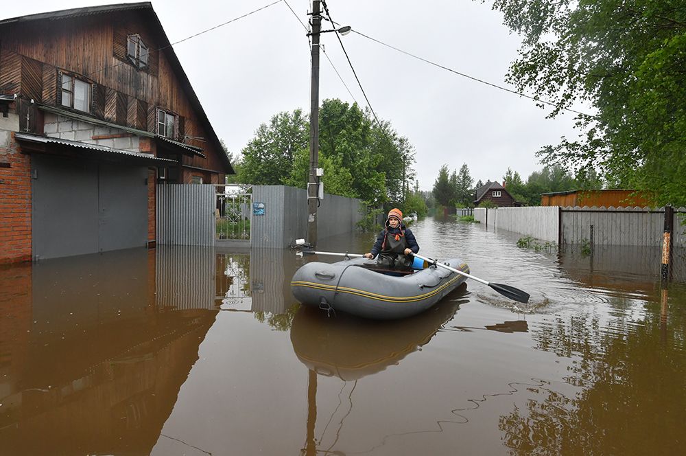 Мальчик плывет на лодке по улице дачного поселка, подтопленного из-за разлива реки Воря в Щелковском районе Московской области.