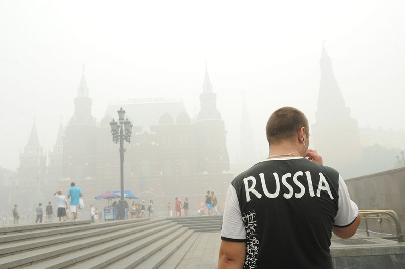Прохожие на Манежной площади в Москве, окутанной дымом из-за лесных пожаров.