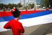 Казаки почётного караула Кубанского казачьего войска разворачивают триколор на Главной городской площади Краснодара во время празднования Дня Государственного флага РФ.
