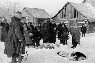 Бойцы Калининского фронта и местные жители осматривают трупы замученных гитлеровцами мирных жителей освобожденной деревни.