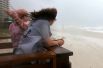 Пара наблюдает за приближением шторма на пляже Орандж-Бич, штат Алабама.