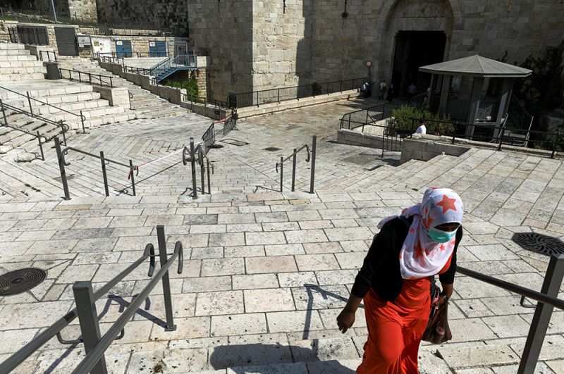 Уважительной причиной выхода из дома являются участие в различных религиозных церемониях и обрядах. На фото: женщина идет по пустынной площади в Старый город Иерусалима. 