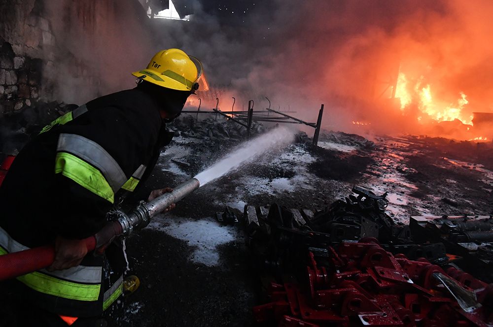 Пожарный тушит пожар на хлопковом заводе в деревне Азат Карагоинлы в Азербайджане, который возник в результате артиллерийского обстрела.