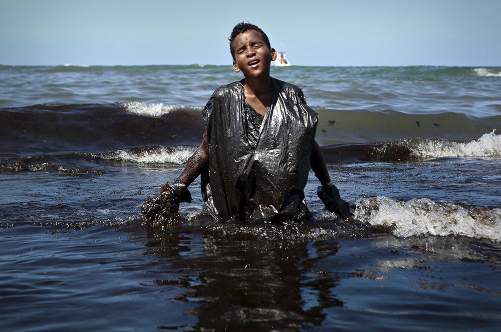 Мальчик участвует в устранении последствий разлива нефти у  пляжа Итапуама в городе  Кабу-ди-Санту-Агостинью, штат Пернамбуку, Бразилия. Особая отметка жюри в категории «Главные новости». 