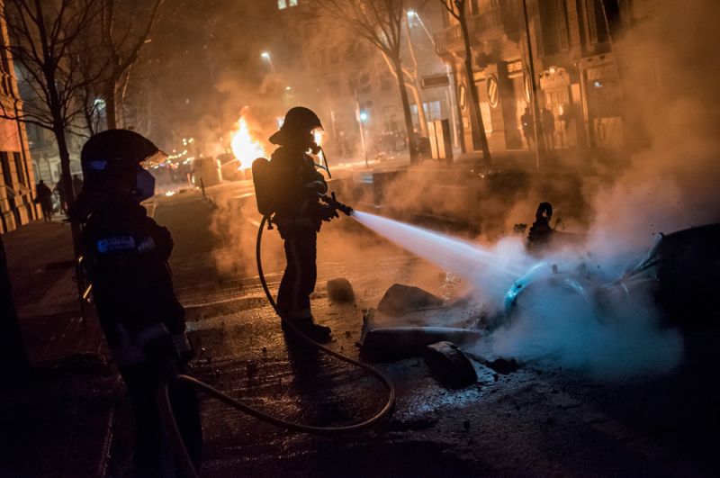 Сотрудники пожарной службы тушат горящие скутеры на одной из улиц Барселоны.