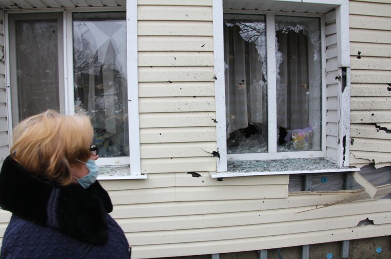 Жительница поселка Еленовка осматривает свой дом, поврежденный артобстрелом.