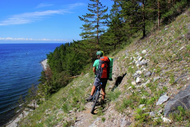 Велосипедист на участке туристического пешего маршрута "Большая Байкальская тропа" в Прибайкальском национальном парке на берегу озера Байкал.