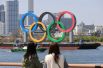 Жительницы Токио смотрят на олимпийские кольца с набережной Дайба.