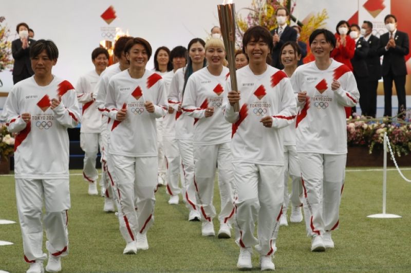 Бывшие члены женской национальной сборной Японии «Надэсико Япония» несут факел в первый день эстафеты Олимпийского огня в Токио-2020.
