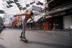 Работник ресторана катается скейтборде на почти пустой улице Каосан во время праздника. 