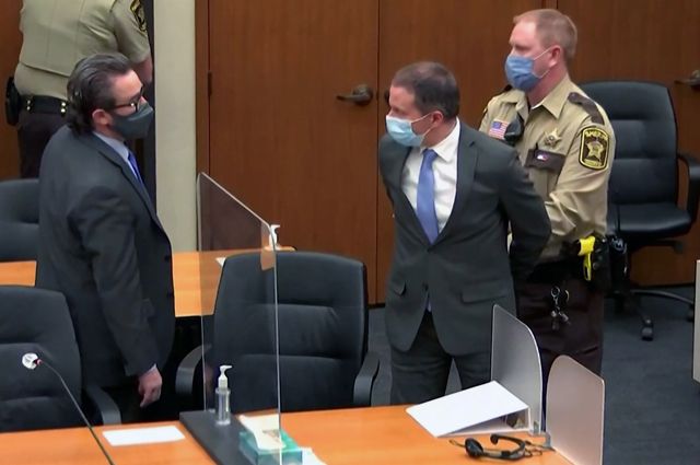 Бывшего офицера полиции Миннеаполиса Дерека Човена уводят в наручниках мимо своего адвоката Эрика Нельсона после того, как присяжные признали его виновным по всем пунктам обвинения.