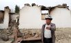 Мужчина стоит у сгоревшего строения в приграничном с Таджикистаном селе Кок-Таш
