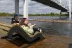 Девушки сидят на затопленной набережной Енисея под Виноградовским пешеходным мостом в центре Красноярска